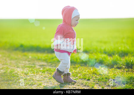 Heureuse petite fille qui marche dans la prairie et à la recherche de Sun Banque D'Images