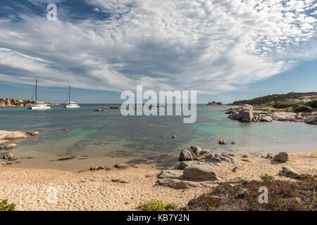 Deux catamaran yachts amarrés au large de la côte de l'île de Cavallo près de corse avec plage de sable et rochers en premier plan, la Méditerranée turquoise Banque D'Images