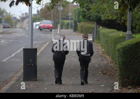 British school les enfants garçons sur la rue messing au sujet de la marche de l'école ensemble deux garçons sur voiture sinistre horizon Banque D'Images