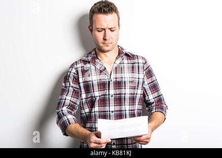 Man holding a choqué certains documents, isolé sur fond gris Banque D'Images