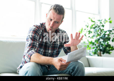 Man holding a choqué certains documents sur canapé salon Banque D'Images