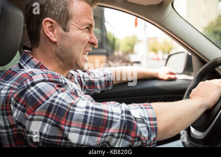 Jeune homme irrité la conduite d'une voiture pilote irritée. Banque D'Images