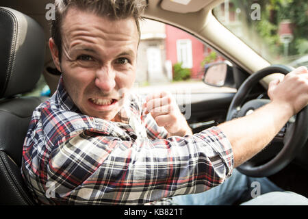 Jeune homme irrité la conduite d'une voiture pilote irritée. Banque D'Images