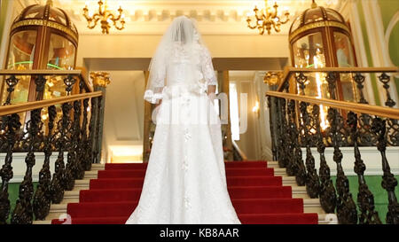 Belle robe de mariée magnifique en remontant la escaliers en pierre d'un bâtiment romantique de mariée robe de mariage. dans monte les escaliers. Jupe et voile se trouvent sur les traces bien que mariée monte à l'étage. Banque D'Images