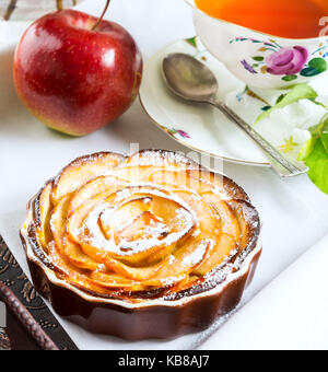 En forme de rose apple pie et une tasse de thé sur le plateau de service plateau de petit-déjeuner avec des pâtisseries sucrées de pomme. Banque D'Images