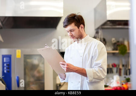 Chef avec presse-papiers faisant l'inventaire à restaurant Banque D'Images