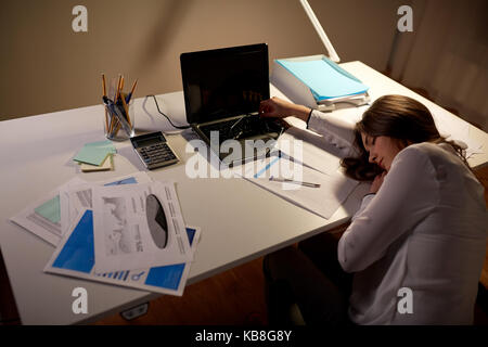 Tired woman sleeping on table office de nuit Banque D'Images