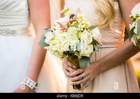 Bridesmaid debout à côté d'une belle bride holding bouquet rustique pastel. Banque D'Images