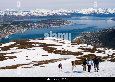 Les randonneurs à pied dans la neige sur le mont Storsteinen avec vue sur la ville sur l'Île Tromsoya en été. Tromso, Troms, Norvège, Scandinavie Banque D'Images