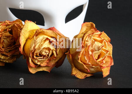 Masque vénitien blanc et sec des roses jaunes sur fond noir Banque D'Images