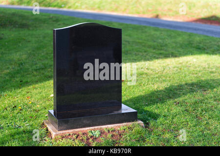 Pierre tombale en granit poli blanc non marqué, baignée de soleil avec de l'herbe verte et les chemins de l'espace de copie sur ou autour de la pierre tombale Banque D'Images