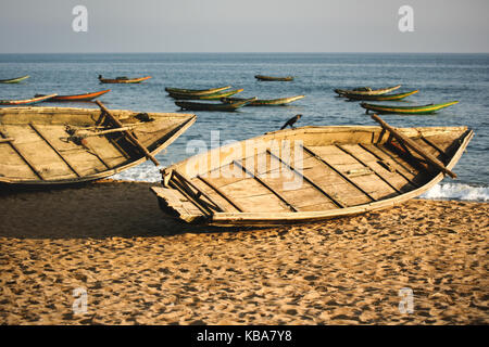 Coucher du soleil jette sa douce lumière dorée sur les indiens traditionnels bateaux de pêche amarrés sur la plage tandis que d'autres flottent dans la mer à puri inde image seascape. Banque D'Images