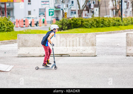 Saguenay, Canada - le 3 juin 2017 : Centre-ville ville parc d'été au Québec avec de jeunes garçons adolescents patinage, effectuant ricks, cascades en scooter sur metal r Banque D'Images