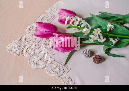 Bouquet de tulipes violet et blanc avec des chocolats à l'hyacinthe nappe brodée d'angle Banque D'Images