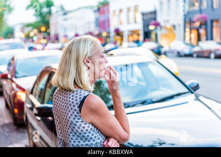 Washington DC, USA - 4 août 2017 : Retour de femme d'âge moyen en 50s à la cigarette au centre-ville de Georgetown et de brique b rue de quartier Banque D'Images