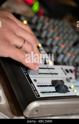 Dj travaillant sur un audiomixer dans une boîte de nuit. close-up de qualité de la musique de réglage les mains à l'aide d'un des boutons de la console de mixage audio Banque D'Images