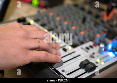 Dj travaillant sur un audiomixer dans une boîte de nuit. close-up de qualité de la musique de réglage les mains à l'aide d'un des boutons de la console de mixage audio Banque D'Images