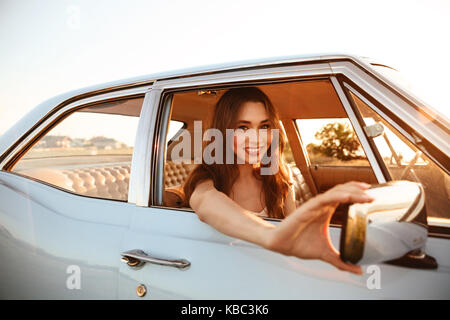 Vue latérale du plaisir femme assise à l'intérieur d'une voiture et en regardant par la fenêtre Banque D'Images