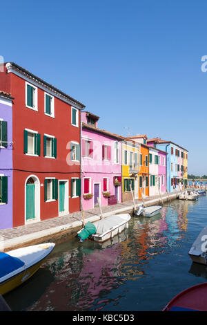 Burano, Venise, Vénétie, Italie maisons et bateaux aux couleurs vives avec des reflets dans un canal dans une vue verticale Banque D'Images