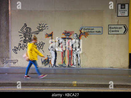 Dame marcher passé Banksy Basquiat travail graffiti sur le mur dans un tunnel sous le Barbican Centre, Londres UK Banque D'Images