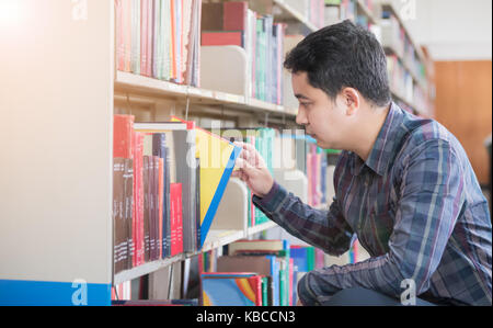 Smart student trouver livre sur l'étagère de la bibliothèque, de l'éducation concept Banque D'Images