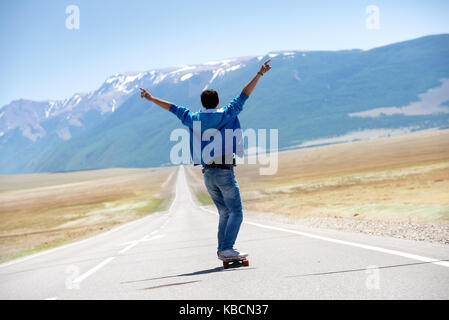 Man skating longboard tout droit la route des montagnes Banque D'Images