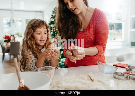 L'enseignement de la mère à sa fille pour faire des cookies. Woman with her daughter making Christmas cookies à l'aide de pâte. Banque D'Images