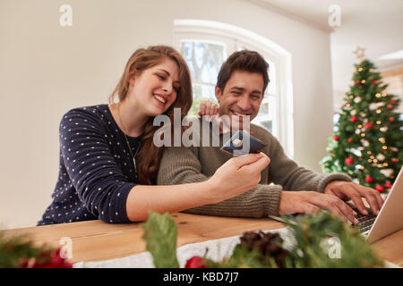 Jeune famille avec un ordinateur portable et une carte de crédit achat en ligne cadeaux de noël et nouvel an. Couple doing online shopping pour Noël