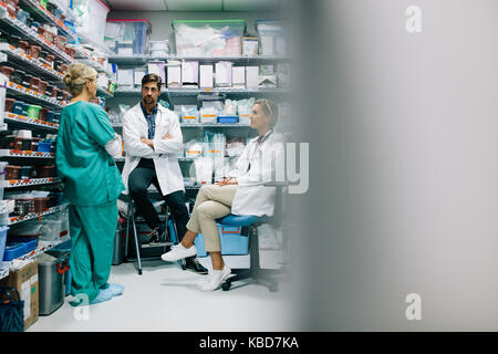 Le personnel de l'hôpital de discuter ces médicaments dans la pharmacie. Trois collègues réunion en pharmacie et de parler. Banque D'Images