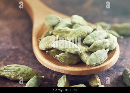 Matières cardamomes vertes dans la cuillère en bois sur fond rustique Banque D'Images