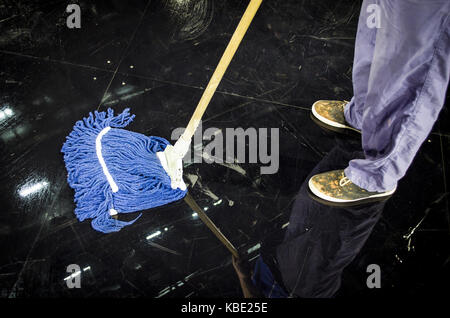 Jeune homme avec mop nettoyage planchers en chambre libre Banque D'Images