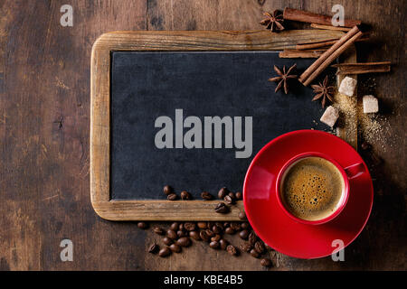 Tableau vintage vide, les grains de café, les épices, le sucre brun et rouge tasse de café noir sur fond de bois ancien. Vue de dessus avec l'espace pour le texte. Banque D'Images