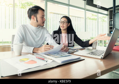 Couple de jeunes designers travaillant au bureau moderne, deux collègues discuter projet amusant sur un ordinateur portable, peu de gens d'affaires de l'équipe de sourire et de regarder Banque D'Images