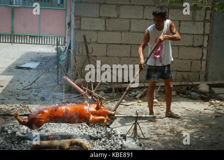 La cuisson d'un cochon à la broche sur un feu ouvert, Angeles, Philippines. Banque D'Images