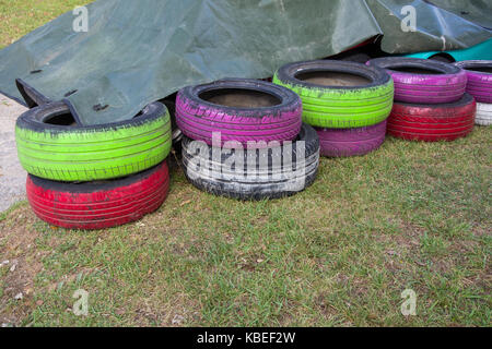 Les vieux pneus de couleur abritées dans pile : peint en vert, violet, blanc Banque D'Images