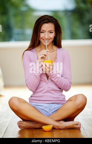 Girl holding orange sat et une paille Banque D'Images