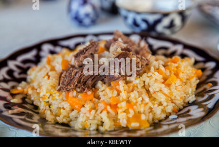 Pilaf ouzbek, un plat traditionnel de la cuisine d'Asie centrale, sur une plaque avec motif oriental Banque D'Images