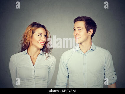 Beau couple est à la recherche à l'autre et souriant tout en se tenant à l'arrière-plan gris Banque D'Images