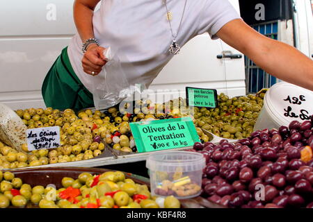 Femme au service d'une large gamme d'olives à la vente à un marché en plein air dans le sud de la france Banque D'Images