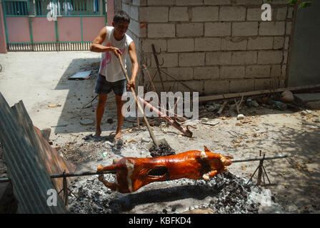 La cuisson d'un cochon à la broche sur un feu ouvert, Angeles, Philippines. Banque D'Images