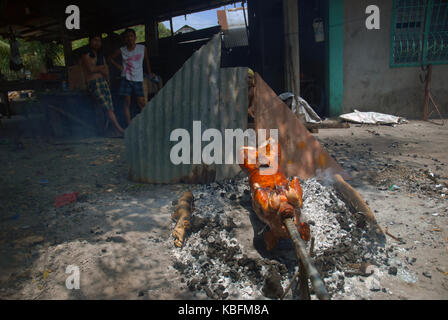 La cuisson d'un cochon à la broche sur un feu ouvert, Angeles, Philippines. Banque D'Images