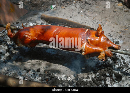 La cuisson d'un cochon à la broche sur un feu ouvert, Angeles, Philippines. Banque D'Images