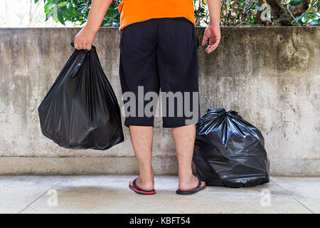 La section basse d'un jeune homme portant un sac à ordures Banque D'Images