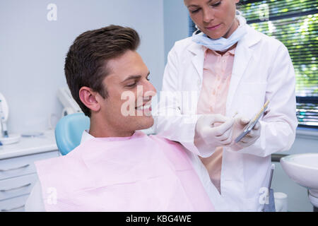 Dentist showing digital tablet au patient à la clinique dentaire Banque D'Images