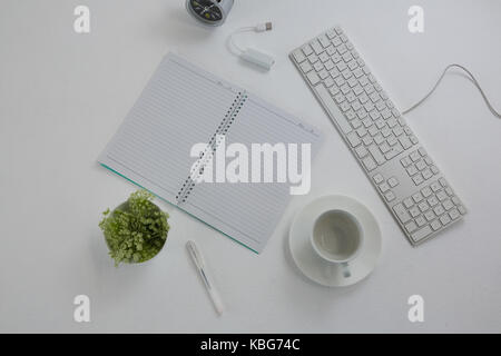 Passage de clavier, de plantes en pot, stylo, livre, tasse à café et soucoupe sur la table Banque D'Images