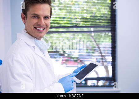 Portrait du docteur à l'aide de tablet debout contre le mur en clinique Banque D'Images