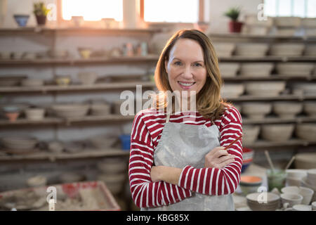 Portrait de femme potter debout avec les bras croisés dans l'atelier de poterie Banque D'Images