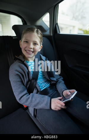 Portrait of teenage girl using mobile phone dans le siège arrière de voiture Banque D'Images