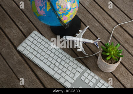 Frais généraux de plantes en pot, globe, clavier et modèle d'avion sur planche en bois Banque D'Images