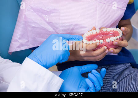 Image recadrée de dentiers dentiste montrant de garçon à la clinique médicale Banque D'Images